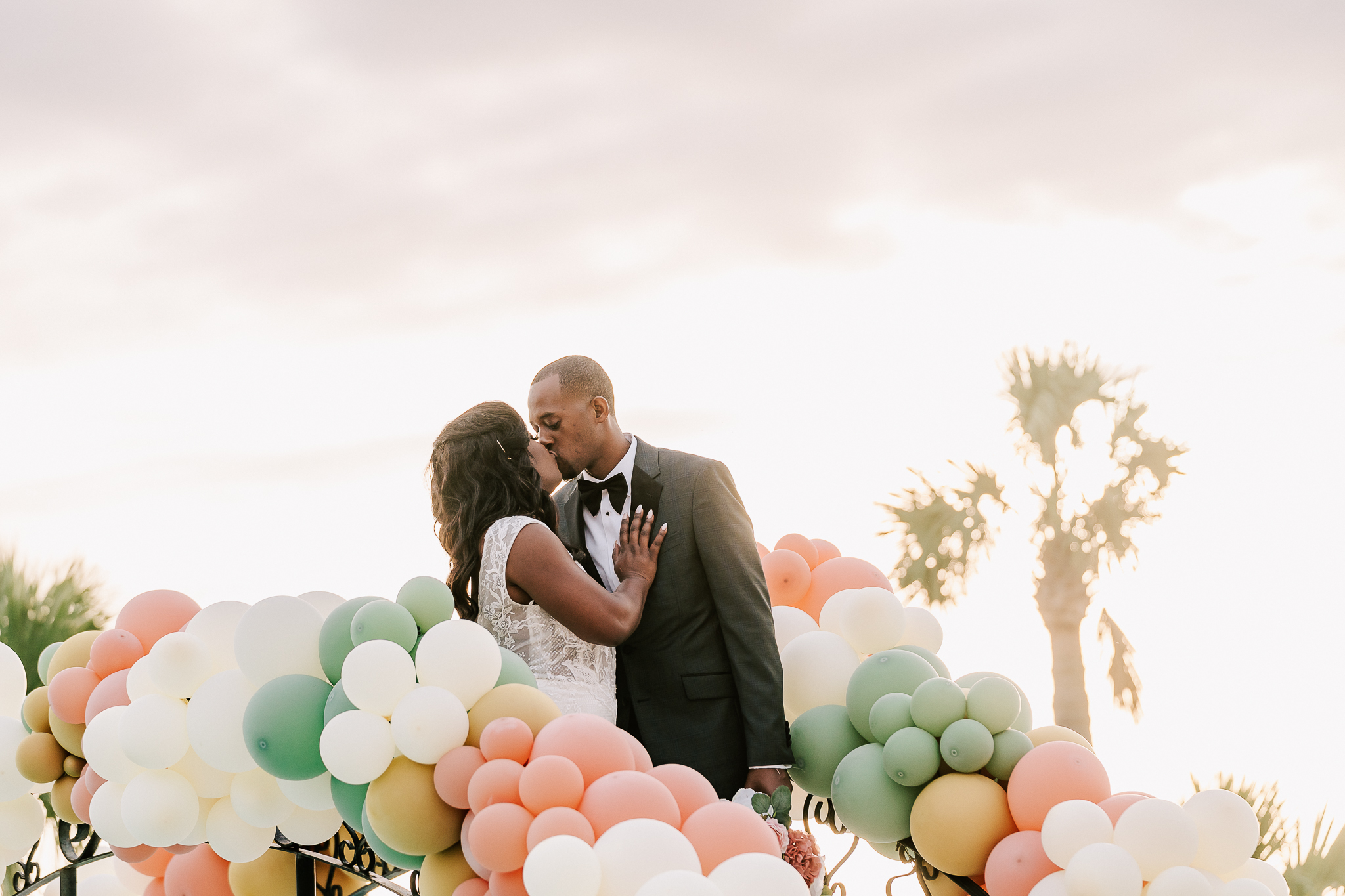 Bride and groom kissing with balloon arch. Palmetto Bluff Wedding in Bluffton, SC.