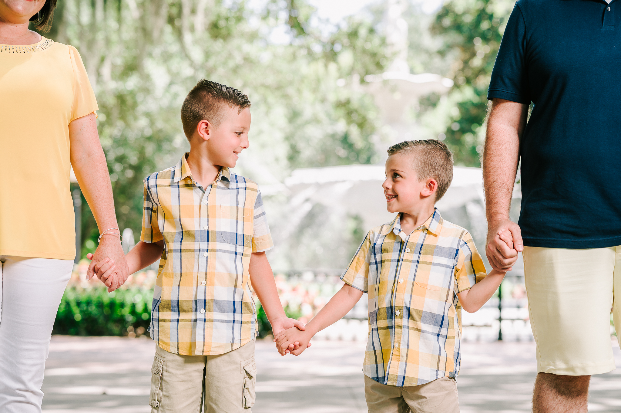 Little boys holding hands with parents standing in front of the fountain at Forsyth Park in Savannah, GA.